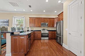 A kitchen with wooden cabinets, stainless steel appliances, and a wooden floor. - Driftwood Haven at Rivers Bend - Steinhatchee (Steinhatchee)