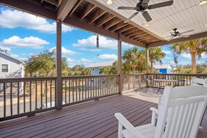 A covered outdoor area with a wooden deck, white chairs, a table, and ceiling fans. - Driftwood Haven at Rivers Bend - Steinhatchee (Steinhatchee)