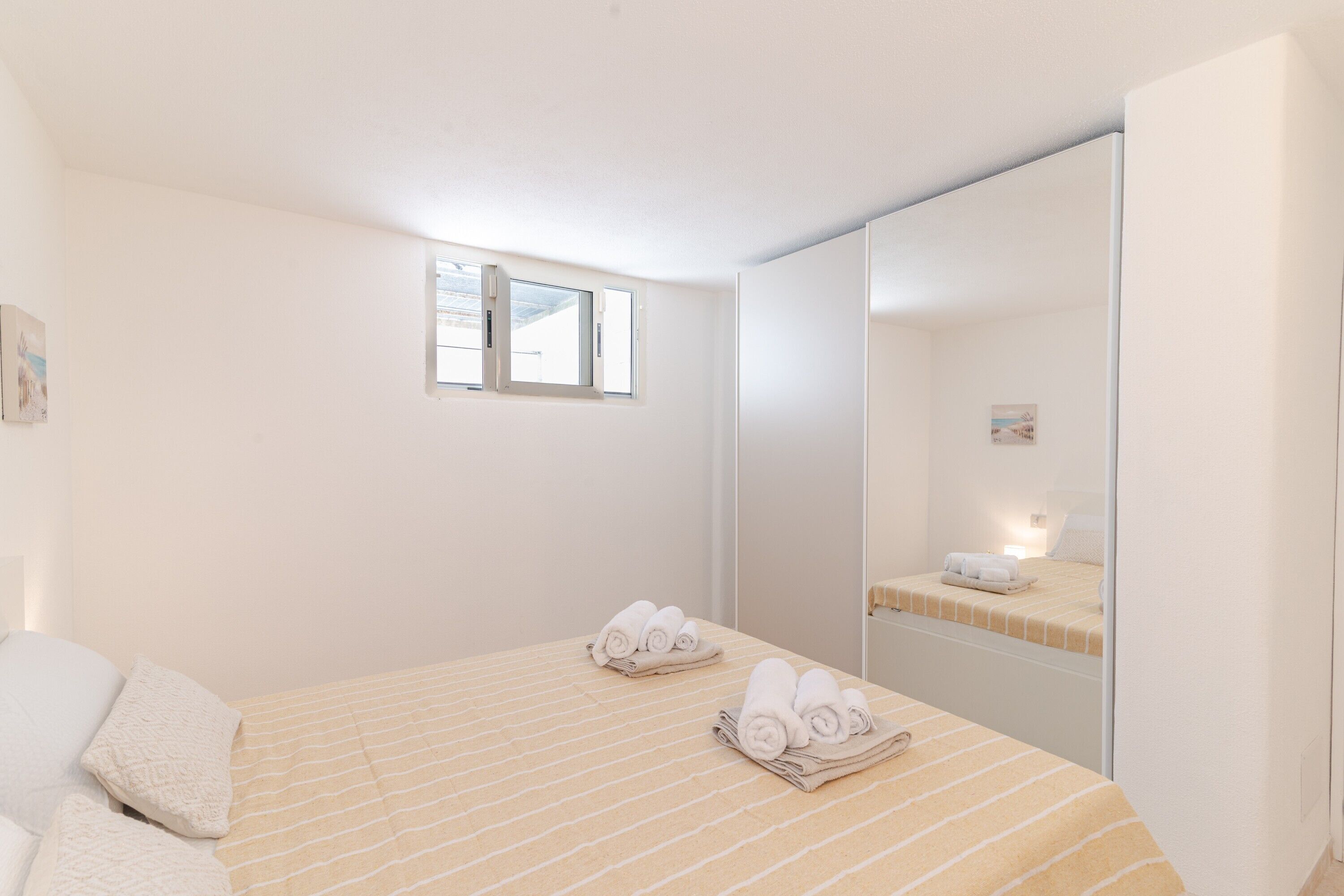 A bedroom with a bed, a window, and a mirror.