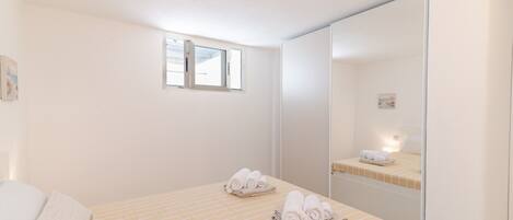 A bedroom with a bed, a window, and a mirror.