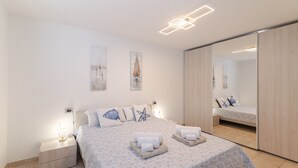 Un dormitorio con cama, mesita de noche, espejo y una obra de arte en la pared.