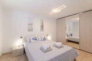 Un dormitorio con cama, mesita de noche, espejo y una obra de arte en la pared.
