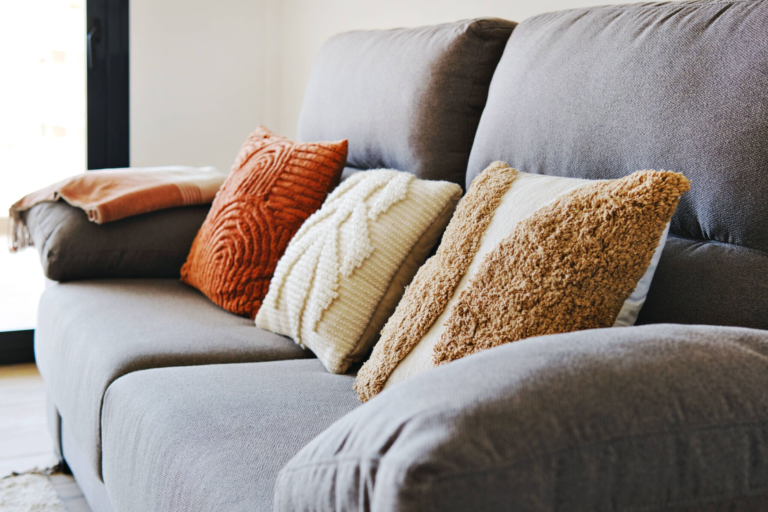 A gray sofa with four cushions in different textures and colors.