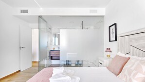 Une chambre à coucher moderne avec un grand lit, une douche en verre et une salle de bain au design minimaliste.