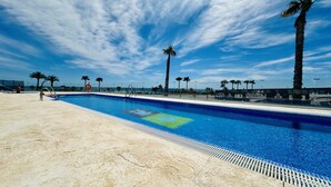 Una piscina con cielo azzurro e palme sullo sfondo.