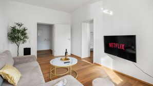 A modern living room with a flat-screen TV displaying the Netflix logo, a sofa, a coffee table, and a small plant. - EVORA - 4 bedrooms - ARCADE - modern (Burgau)