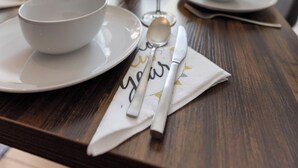 A dining table set with white plates, bowls, and cutlery, with a napkin featuring the word "you" and a spoon. - EVORA - 4 bedrooms - ARCADE - modern (Burgau)