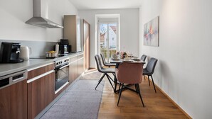 A modern kitchen with a dining area, featuring a built-in oven, a coffee machine, and a dining table with chairs. - EVORA - 4 bedrooms - ARCADE - modern (Burgau)