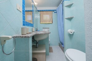 Ein Badezimmer mit Waschbecken, Toilette und Duschvorhang.