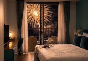 Un dormitorio con cama, escritorio y vista a fuegos artificiales.