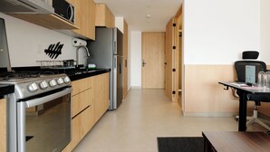 A modern kitchen with wooden cabinets, a stainless steel stove, and a black countertop. - Via Insurgentes by Wynwood House (Mexico City)