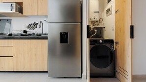 A modern kitchen with a stainless steel refrigerator, wooden cabinets, and a built-in washing machine. - Via Insurgentes by Wynwood House (Mexico City)