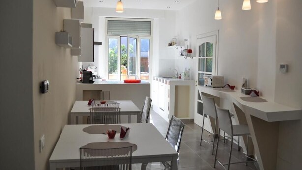Une cuisine moderne avec des meubles blancs, un coin repas comprenant une table et des chaises, et un éclairage suspendu.