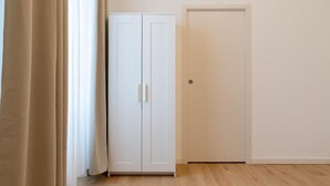 Une pièce avec un plancher en bois, une armoire blanche et une porte fermée.