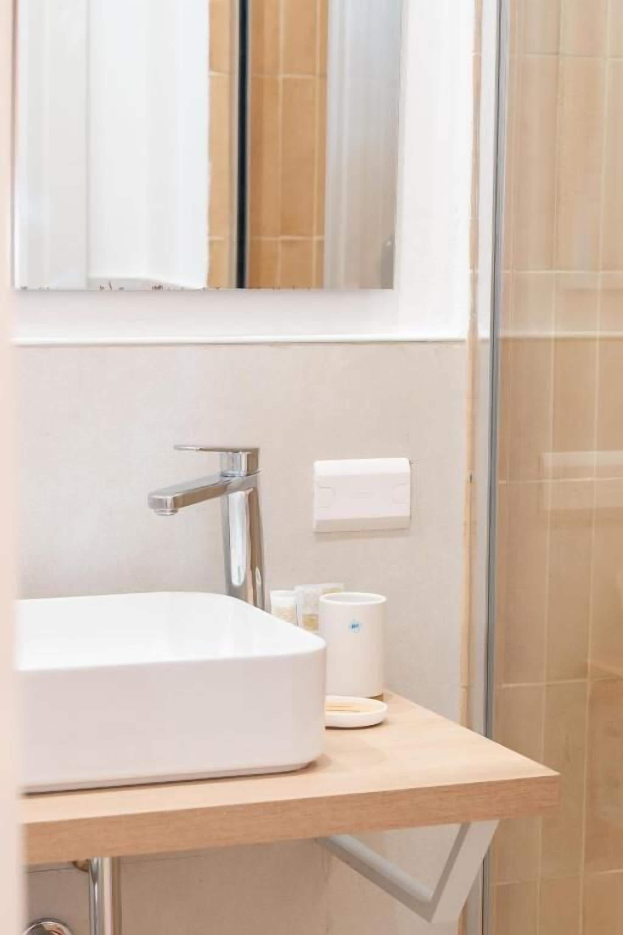 A bathroom with a white sink, a mirror, and a glass shower enclosure.