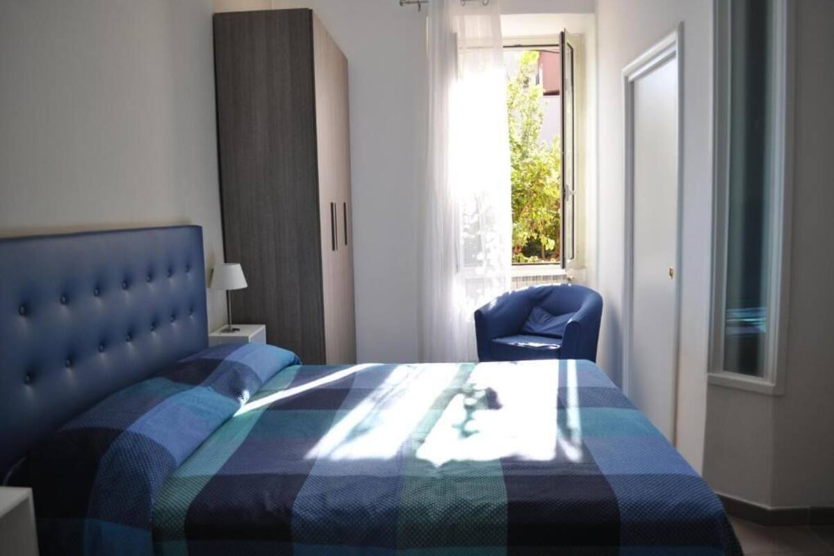 Une chambre à coucher comprenant un lit, une table de chevet, une chaise, une armoire et une fenêtre donnant sur un paysage verdoyant.