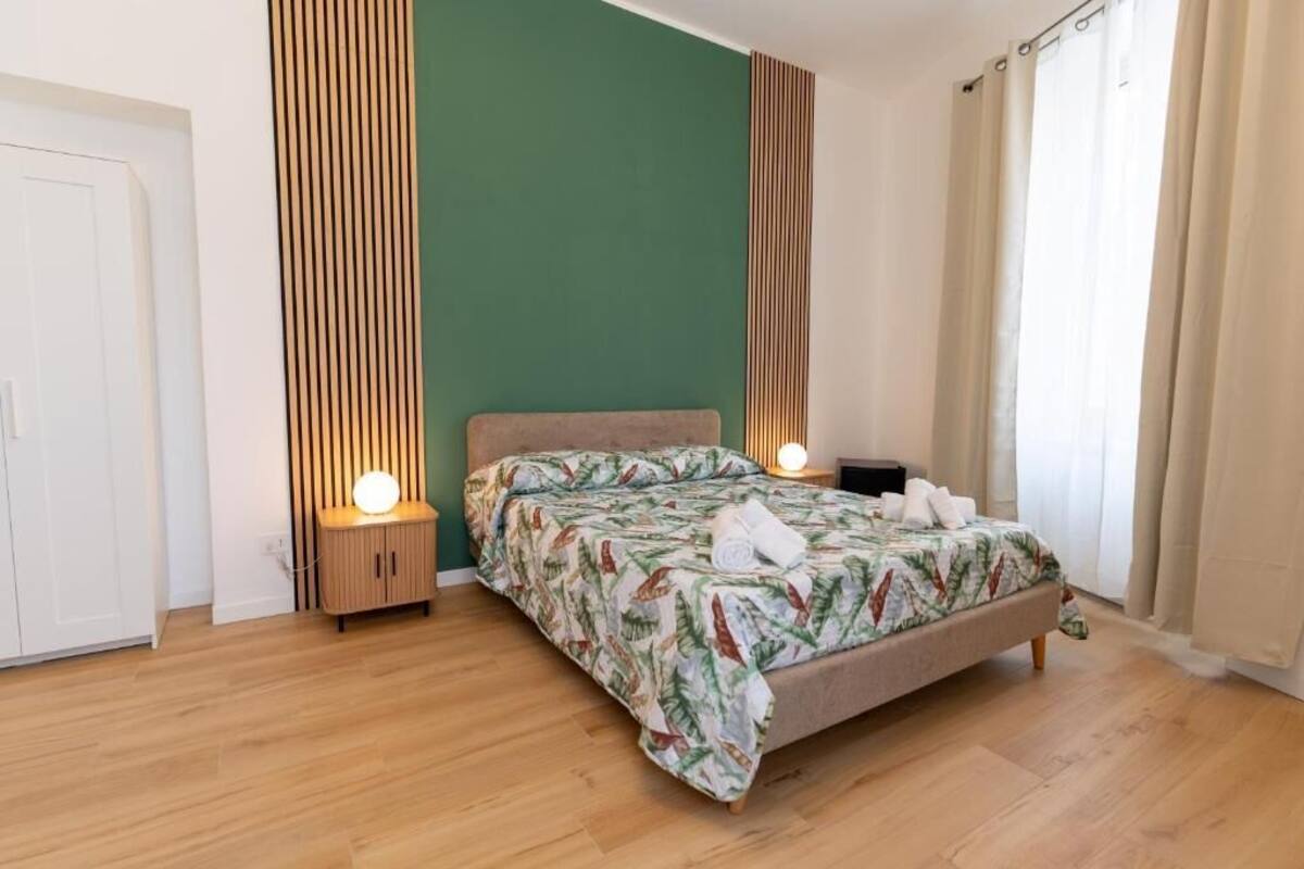 Une chambre à coucher avec un lit, des tables de chevet, une armoire et une fenêtre avec des rideaux.