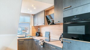 A modern kitchen with a built-in oven, a coffee maker, and a tablet on the counter. - Apartment "Inselstern" on Borkum – 2 Bedrooms, Modern Kitchen, Wi-Fi (Borkum)