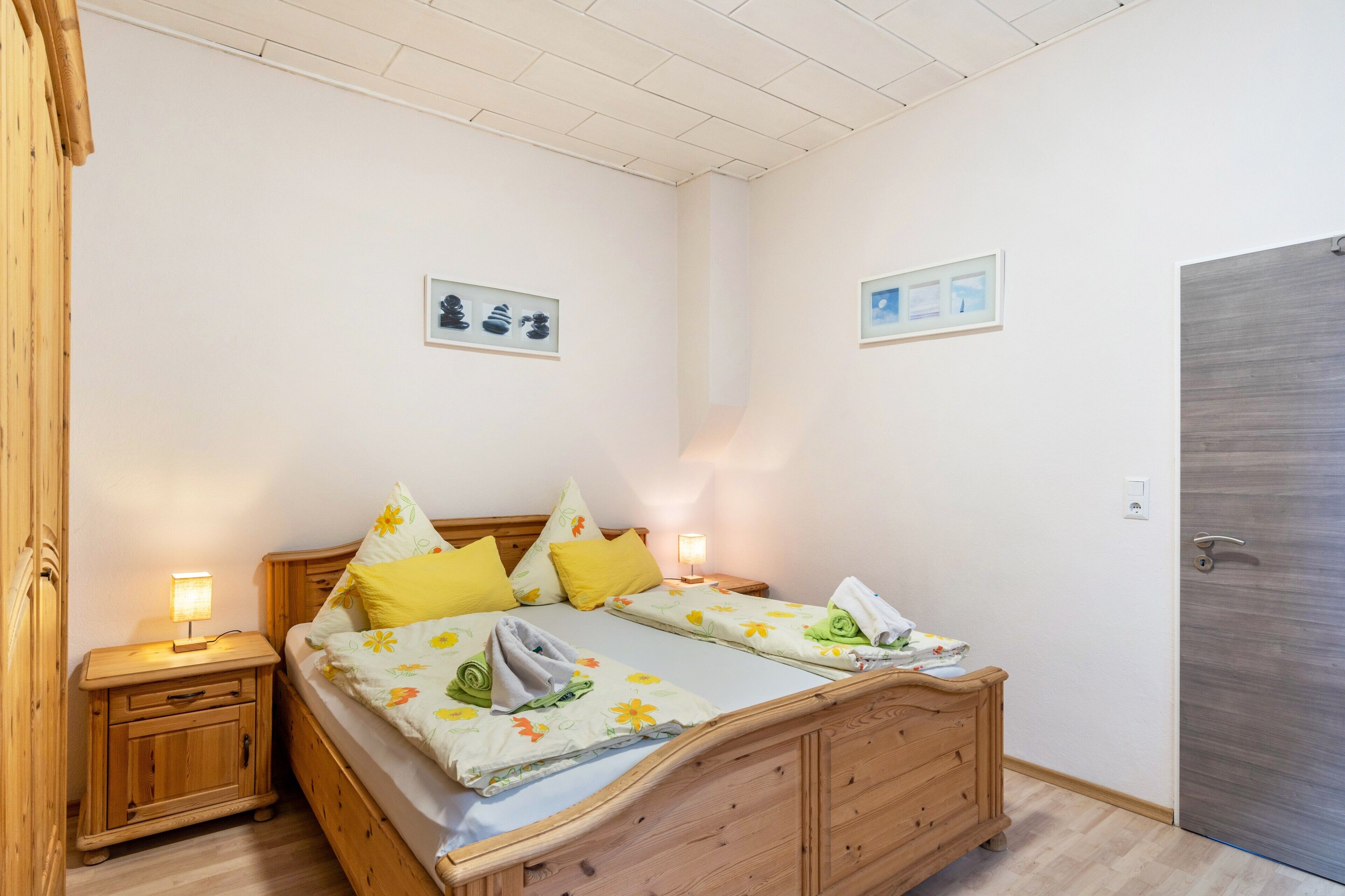 Een slaapkamer met een houten bed, twee nachtkastjes en een deur.