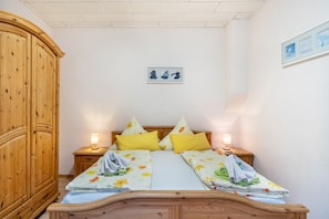 Une chambre à coucher avec un lit en bois, deux tables de chevet avec des lampes, une armoire en bois et un tableau encadré au mur.