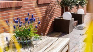 A wooden table with a potted plant and a brick wall in the background. - Holiday Home 'Südstrand' on Borkum for 2–4 Guests, 2 Bedrooms (Borkum)