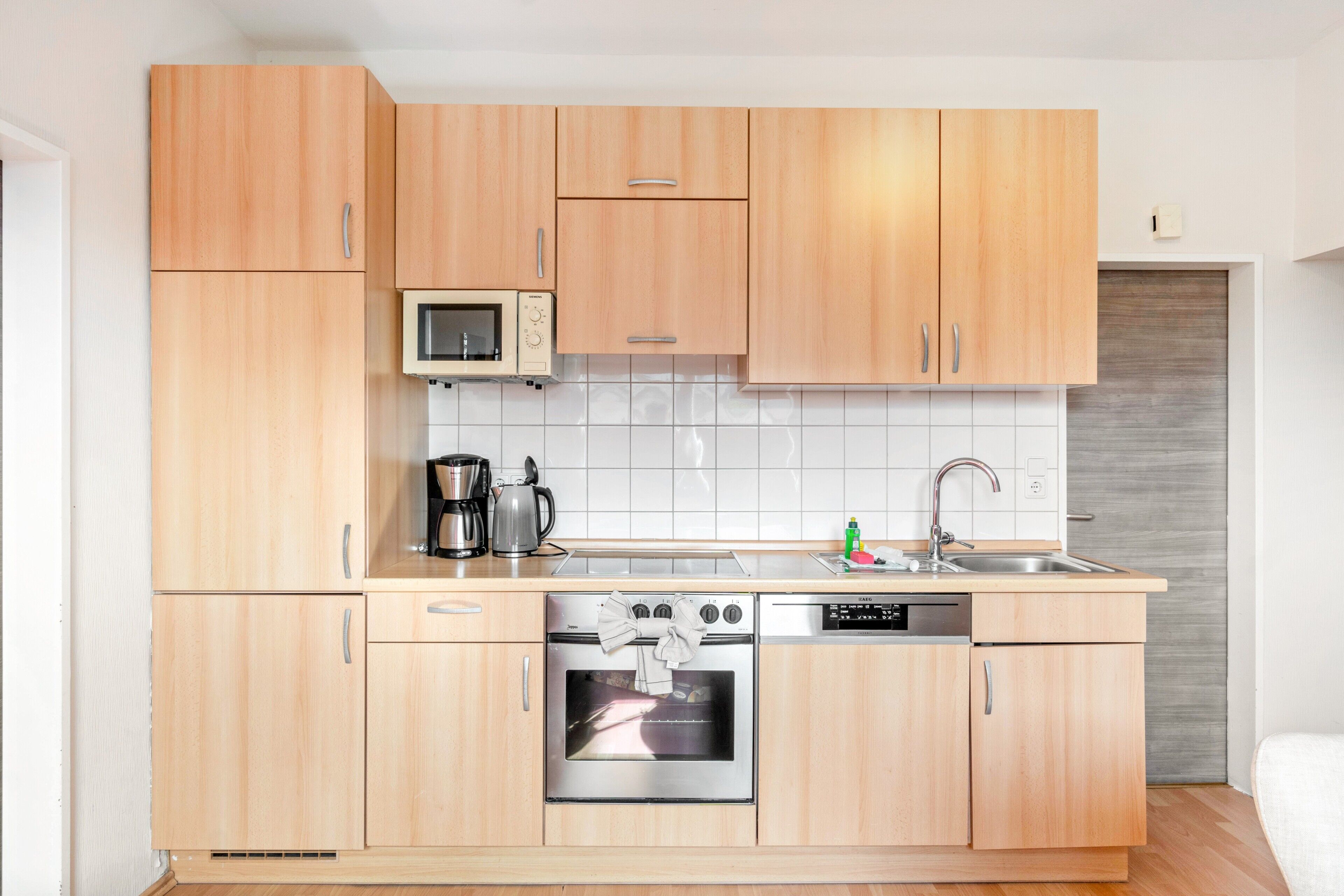 Une cuisine compacte avec des meubles en bois, un four à micro-ondes, une cuisinière et un lave-vaisselle.