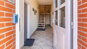 A narrow hallway with a tiled floor, a door on the left, and a staircase leading to an upper level. - Holiday Home 'Südstrand' on Borkum for 2–4 Guests, 2 Bedrooms (Borkum)