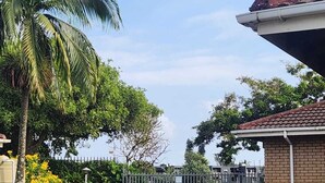 A gated entrance with a brick building and a palm tree. - 5 Beach Dunes (Richards Bay)