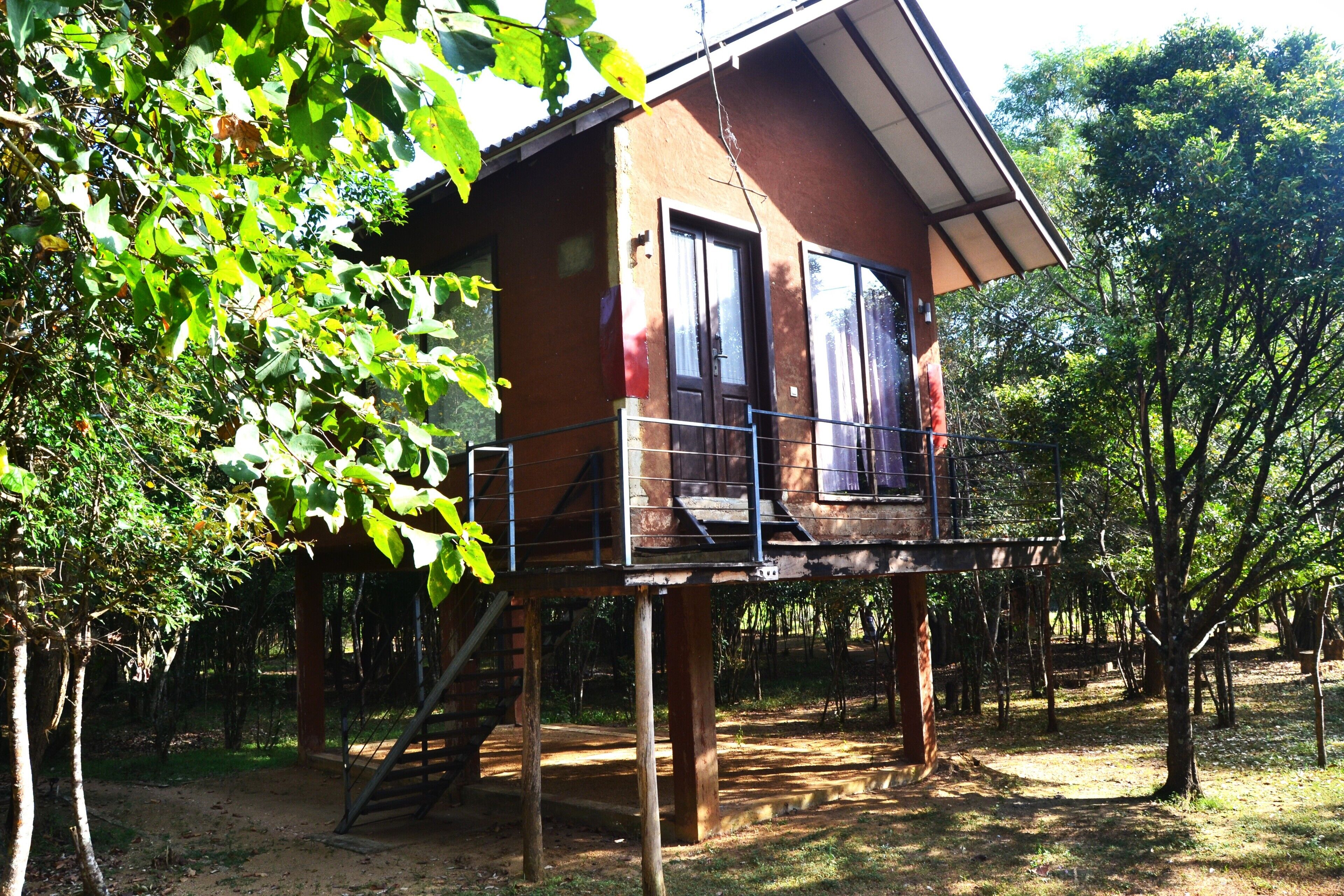 A wooden cabin with a balcony, surrounded by trees.