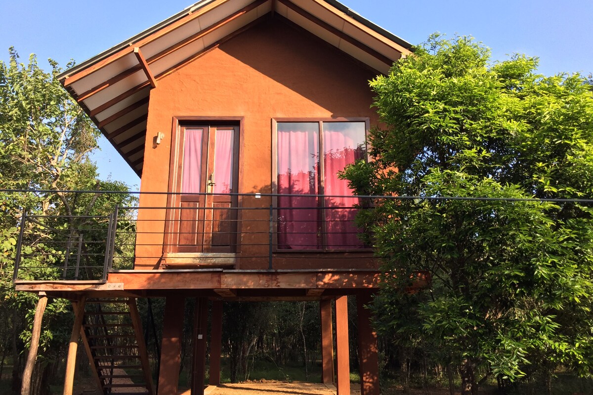 Een houten huis met twee verdiepingen, een balkon, grote ramen en een deur.