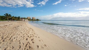 A beach with footprints, palm trees, and buildings in the background. - New Mareazul Resort swim up short walk to beach 2 bdrm 2bath Casa Mistica (Playa del Carmen)