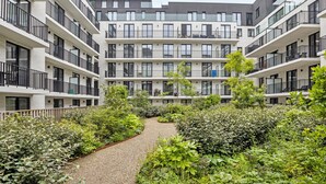 A multi-story residential building with balconies, a central garden path, and surrounding greenery. - The Green 15 0301 met garage (Nieuwpoort)
