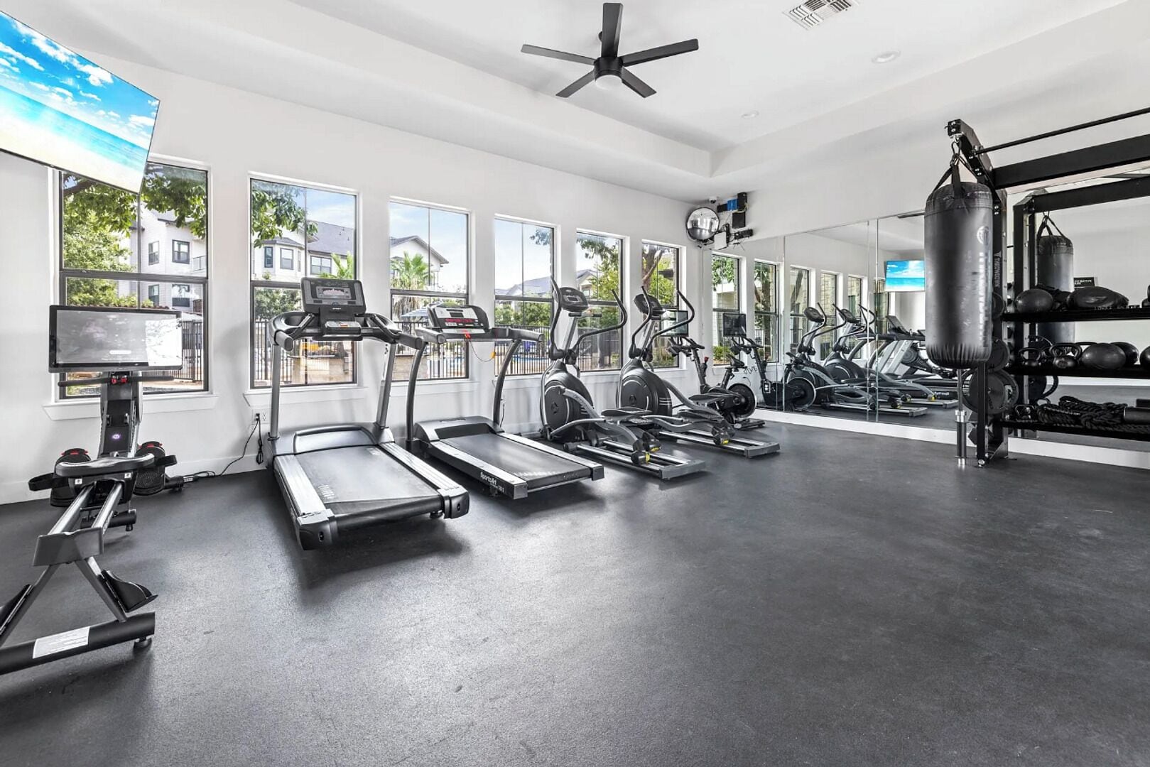 A gym with treadmills, elliptical machines, and a punching bag.