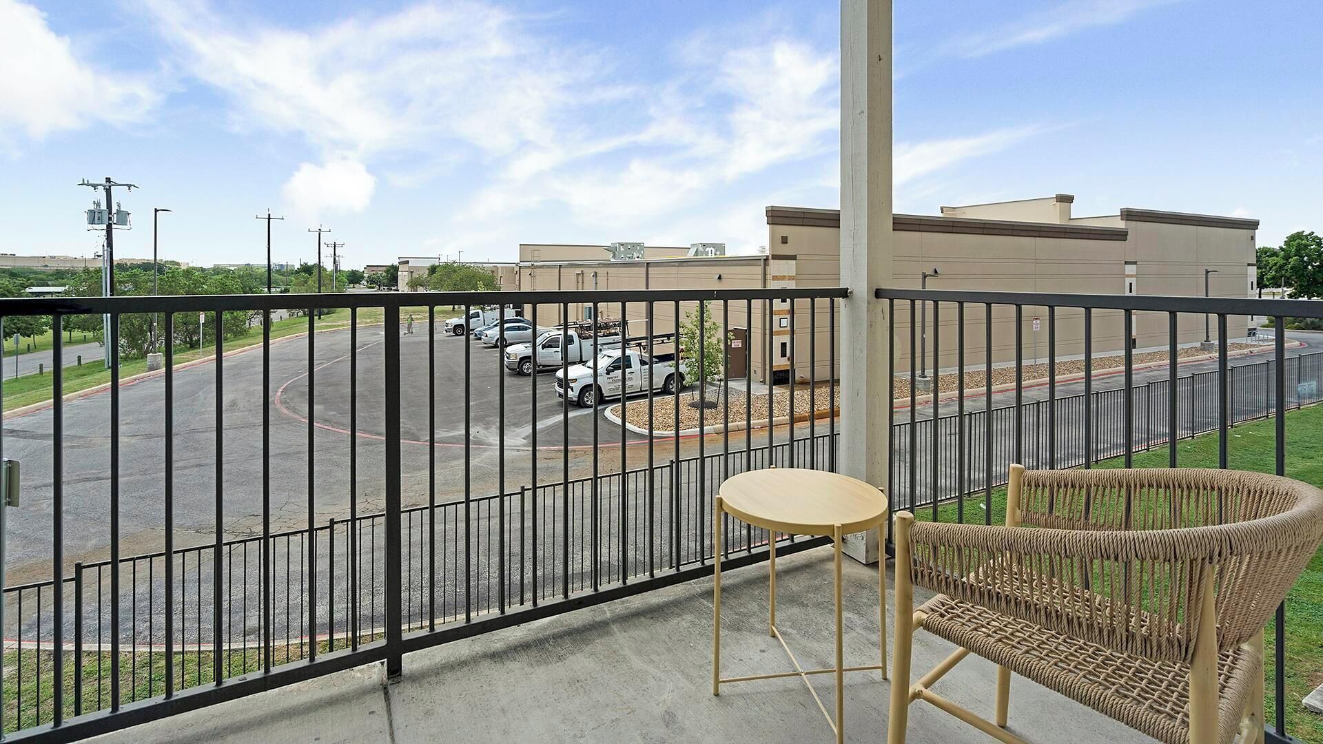 A balcony with a view of a parking lot and a building.