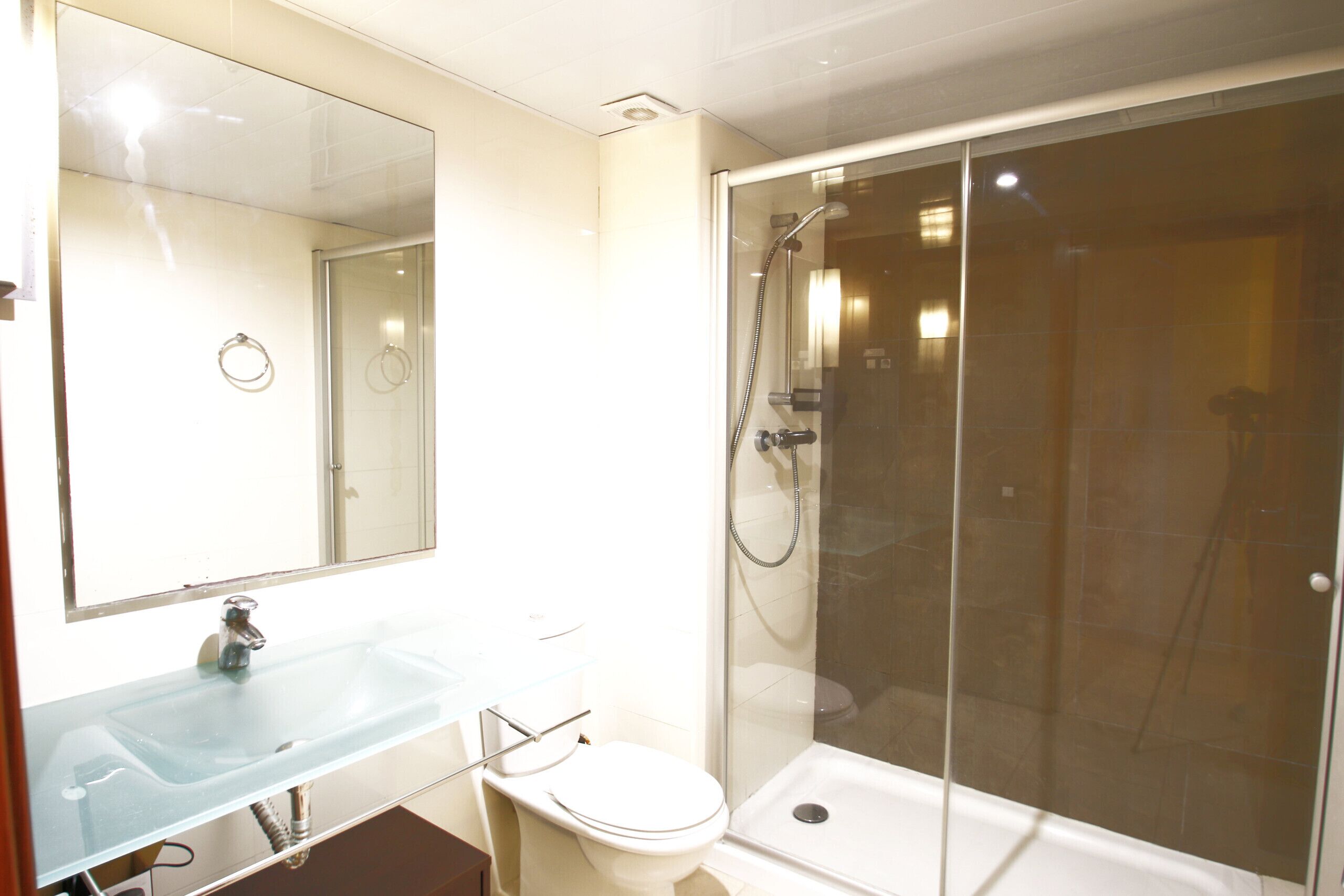 Ein Badezimmer mit Duschkabine aus Glas, einem Waschbecken und einer Toilette.