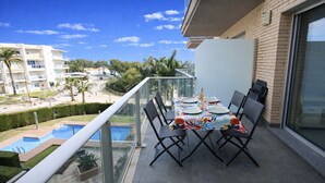 A balcony with a table set for two, overlooking a swimming pool and a residential area. - Apartment Panoramic 26 by Parc Mont-roig (Miami Playa)