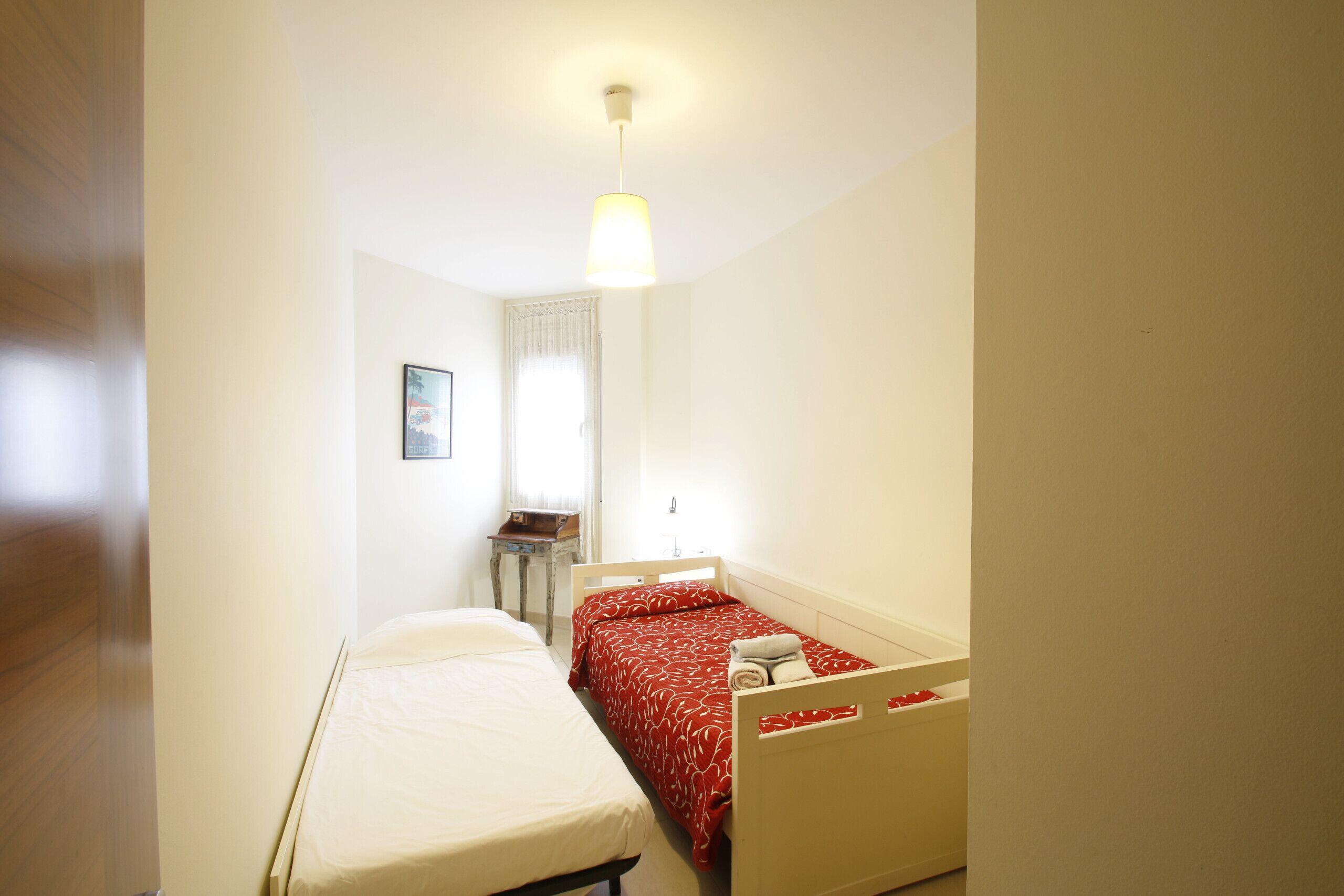 Ein kleines, sauberes Zimmer mit zwei Betten, einem Schreibtisch und einem Fenster.