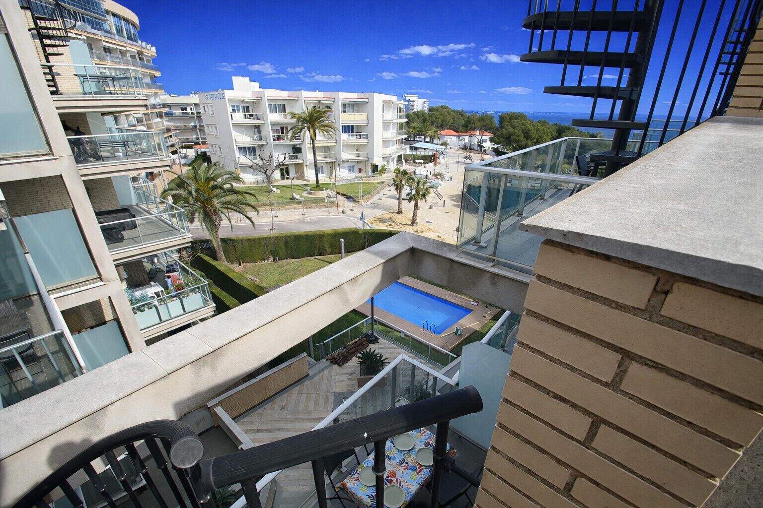 Un immeuble d’appartements moderne doté d’une piscine sur le toit, de balcons en verre et offrant une vue sur la mer.