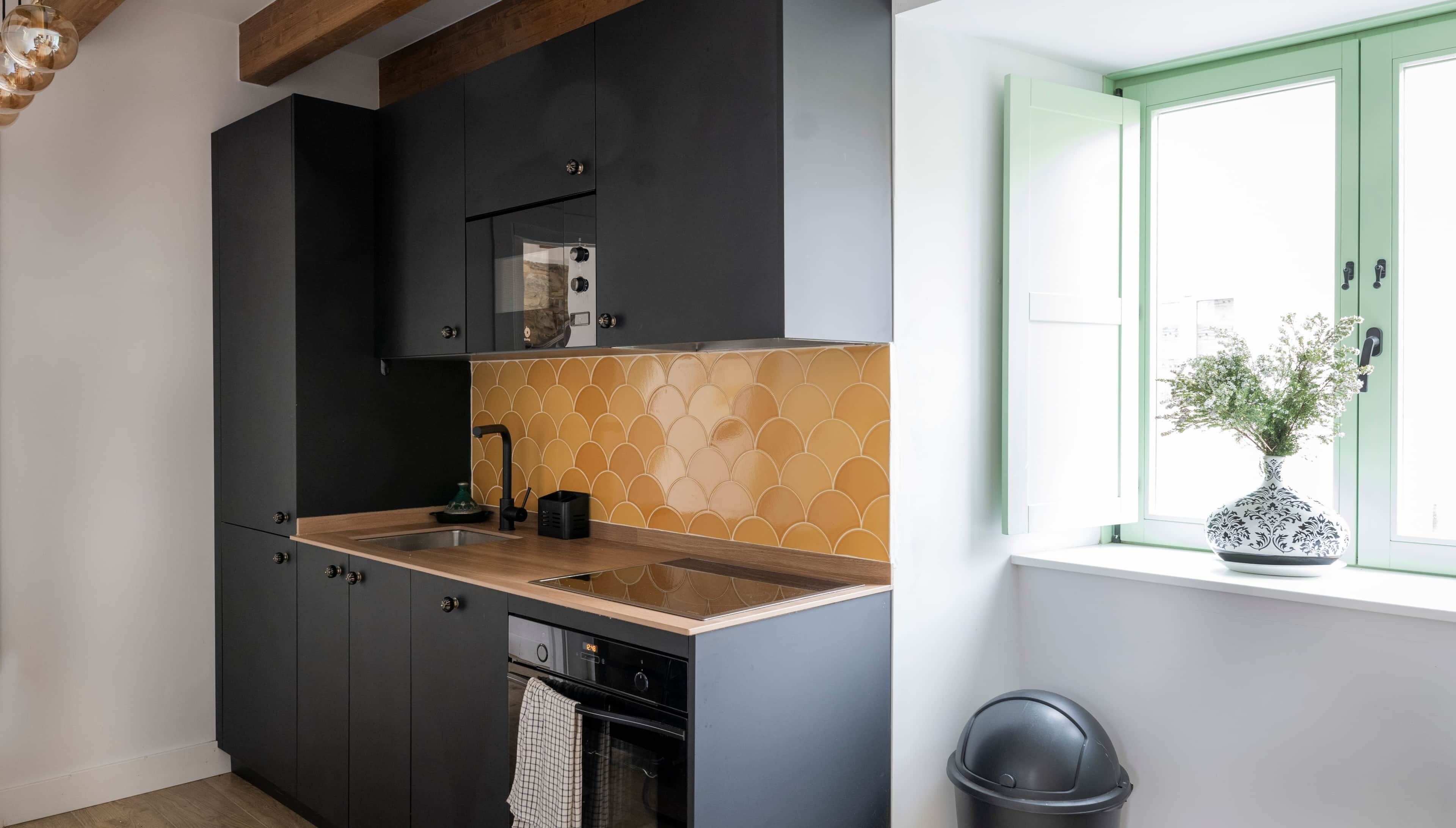 Een moderne keuken met donkere kastjes, een houten aanrechtblad en een spatwand met een golfpatroon.
