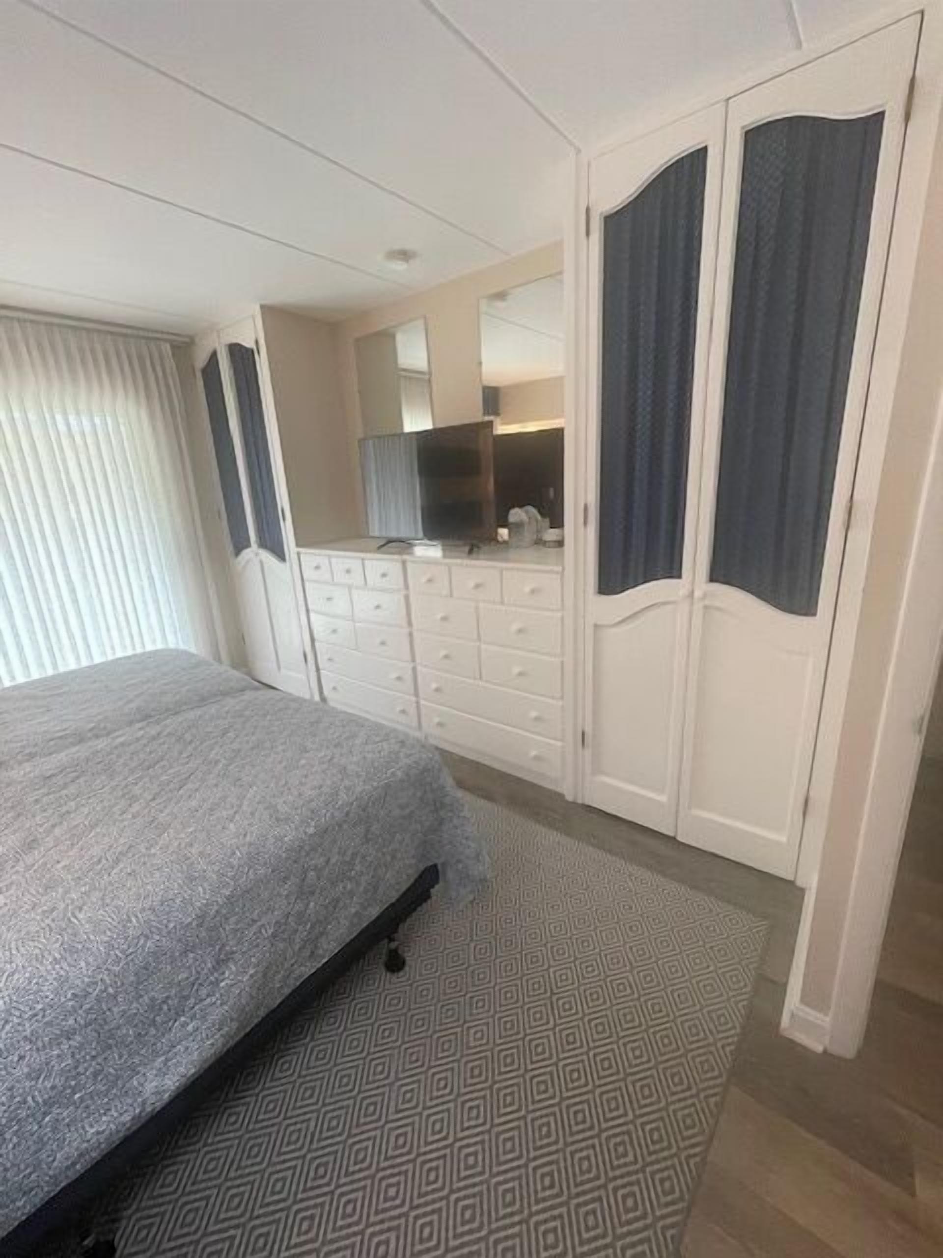 A bedroom with a bed, dresser, and wardrobe.