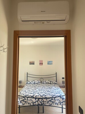A bedroom with a bed, a wooden door frame, and an air conditioning unit above the door. - Enjoy House - close to the lake and all amenities (Desenzano del Garda)