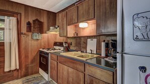 A kitchen with wooden cabinets, a stove, a sink, and a refrigerator. - Stepaway Vacation Rentals - Frog Hollow on Finley Lake (St Germain)