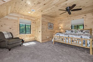 A bedroom with a bed, a chair, a ceiling fan, and large windows. - An Adventure Awaits -  Stepaway Vacation Rentals (St.Germain)