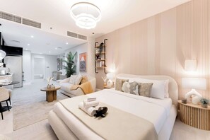 A modern bedroom with a large bed, bedside tables, a built-in shelf, and a view into the living area. - Free housekeeping visits during your stay - StayShort - Stunning Studio Unit in Business Bay that Sleeps 2! (Business Bay)