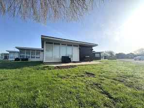 Een modern gebouw met grote ramen en een plat dak, omgeven door een verzorgd gazon.