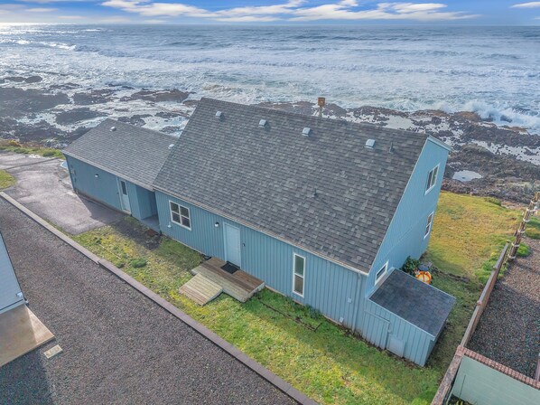A single-story blue building with a sloped roof, a front porch, and a small deck.