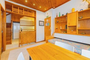 Eine kleine Küche mit Holzschnitzerei, einem eingebauten Kühlschrank und einem Essbereich mit Holztisch und Stühlen.