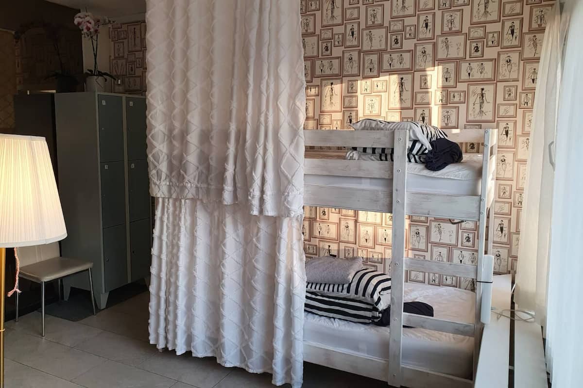 Une chambre avec un lit superposé, une table de chevet, une lampe et une armoire.