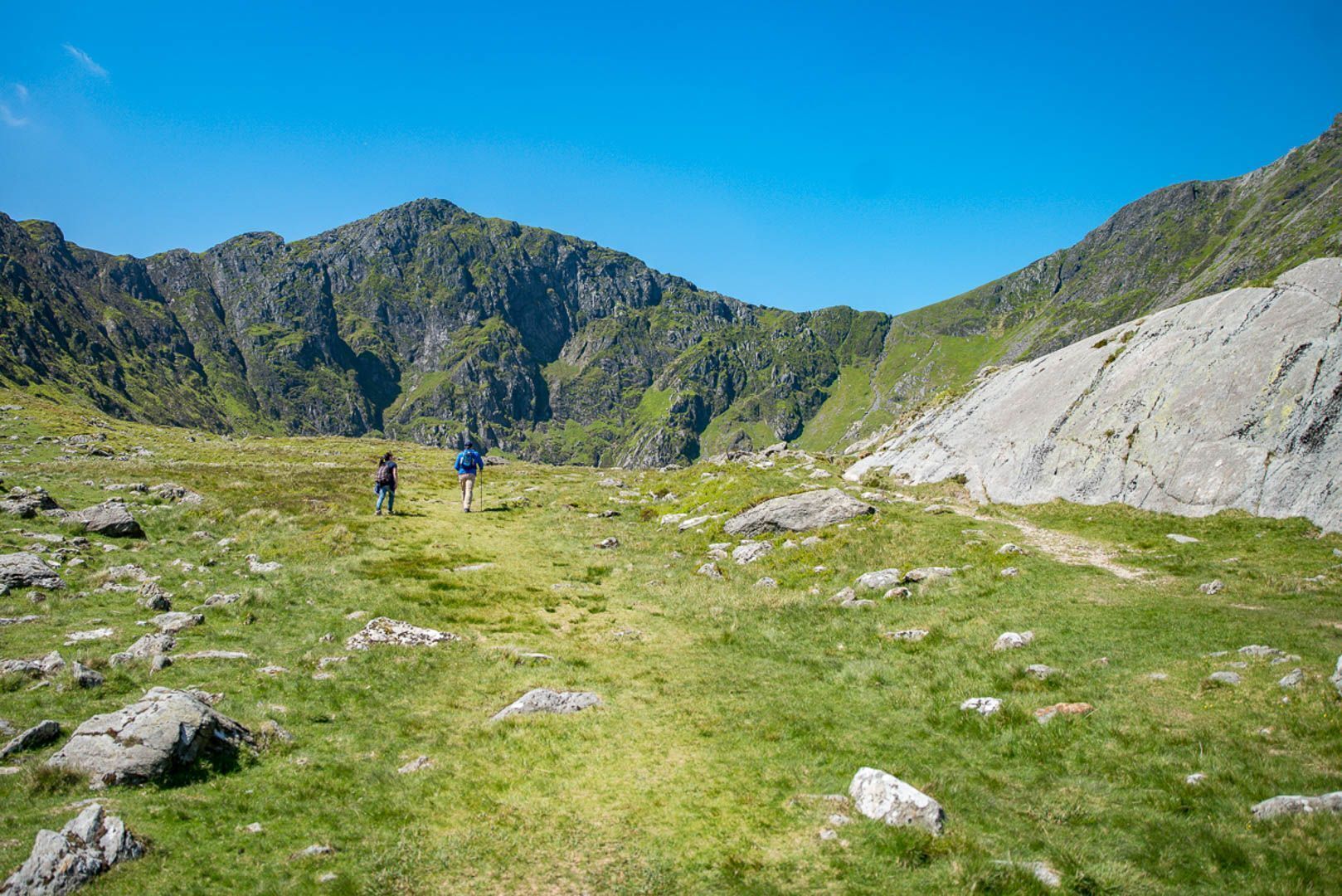 Paisatge montanyós amb excursionistes i terreny rocos.