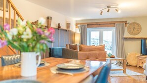 Ein gemütliches Wohnzimmer mit einem Holzespeisetisch, einer Couch und einem Fernseher.